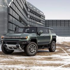 the new hummer truck is parked in front of a large building with grain silos