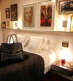 a black and white bed in a bedroom with pictures on the wall above it's headboard