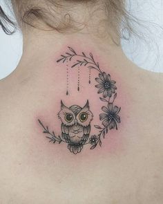the back of a woman's neck with an owl and flowers tattoo on it
