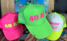 three hats with the number forty four on them, one in neon green and one in pink