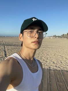 a man wearing glasses and a baseball cap on the beach with sand in the background