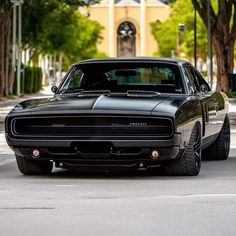 a black muscle car parked on the side of the road in front of a building