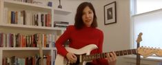 a woman is playing an electric guitar in front of bookshelves