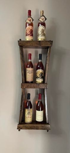 three wooden shelves holding bottles of liquor on top of each other in front of a wall