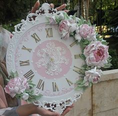 a person holding a large white clock with pink flowers on it