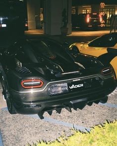 two sports cars parked next to each other on the side of a road at night