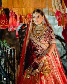 a woman in a red and gold bridal gown standing next to some hanging decorations