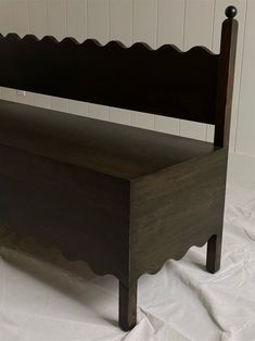 a wooden bed frame with scalloped headboard and foot board on white sheets