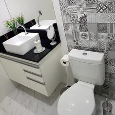 a white toilet sitting next to a sink in a bathroom under a mirror and tiled wall