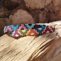 a colorful bracelet sitting on top of a piece of wood