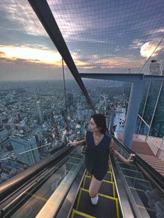 a woman is walking down an escalator in the city at sunset or dawn