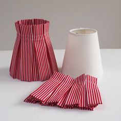two red and white striped lampshades next to each other on a white surface