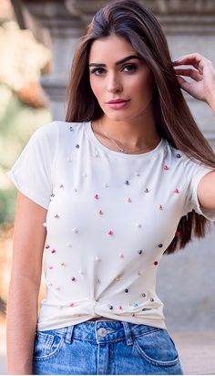 a woman with long brown hair wearing a white t - shirt and blue jeans is posing for the camera