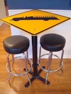 two stools sit under a table with a sign on it that says railroad crossing