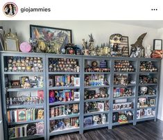 a book shelf filled with lots of books on top of a hard wood floor next to a white wall