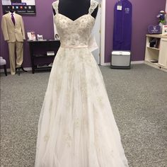 a white wedding dress on display at a bridal event in front of a purple wall