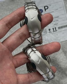 a hand is holding two small silver objects