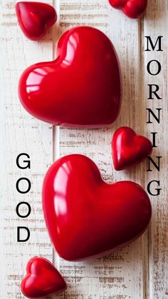three red heart shaped candies sitting on top of a white wooden table with the words good morning