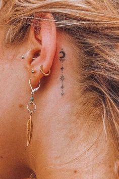 a woman with a tattoo on her ear and behind the ear is a small feather