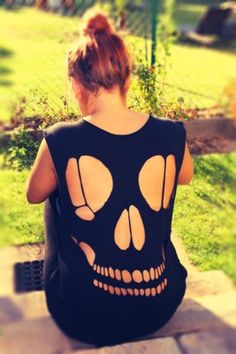 a woman sitting on top of a stone bench wearing a black shirt with skull cutouts