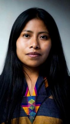 a woman with long black hair wearing a colorful shirt