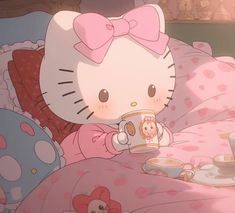 a hello kitty holding a coffee cup on top of a bed with pink sheets and polka dots