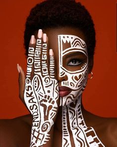 a woman with her hands on her face painted in white and black, posing for the camera