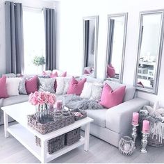 a living room filled with lots of furniture and pink pillows on top of it's couches