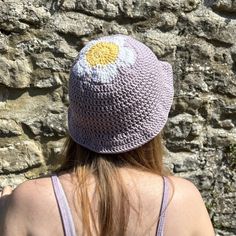 a woman wearing a crocheted hat with flowers on it