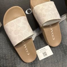 a pair of white and beige slippers with the word coach on them sitting on top of a bed