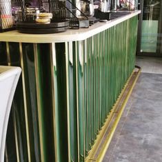 a bar with green and gold bars on the sides, along with white stools