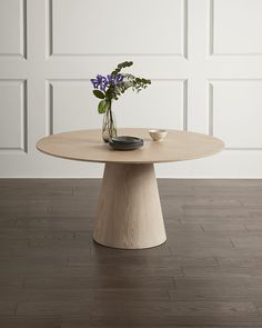 a vase with flowers sitting on top of a table in front of a white wall