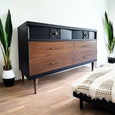 a bedroom with a bed, plant and dresser in it's centerpieces