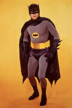 a man dressed as batman standing in front of a yellow background