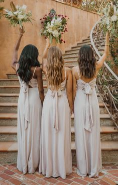 three bridesmaids standing on the steps with their bouquets