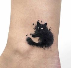 a black cat tattoo on the ankle with watercolor paint splatters all over it