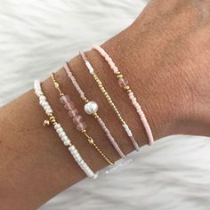 a woman's arm with four different bracelets on top of each other,