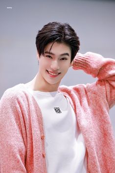 the young man is wearing a pink cardigan sweater and white t - shirt, posing for