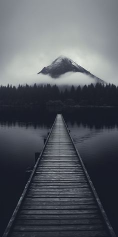 a long dock sitting on top of a lake next to a mountain covered in fog