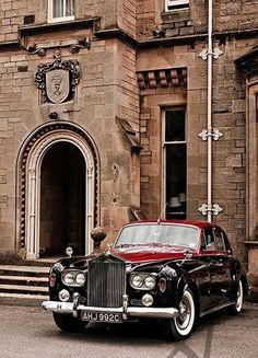 an old black car parked in front of a building