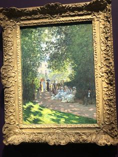 a painting on display in a museum with people walking around and sitting under the trees