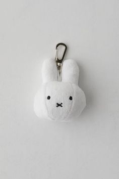 a white stuffed animal keychain hanging from a hook