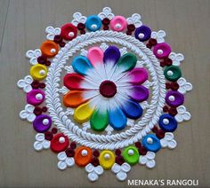 a colorful flower made out of yarn on a wooden surface with white string and beads