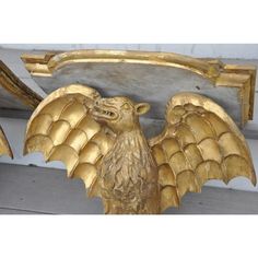 a golden eagle sculpture on the side of a wooden building with gold paint and wood trim around it's wings