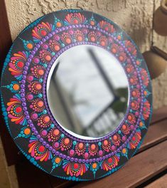 a colorful mirror sitting on top of a wooden table