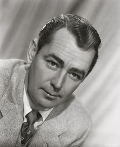 an old black and white photo of a man in a suit looking at the camera