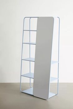 a white book shelf sitting on top of a table next to a wall mounted mirror