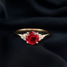 a close up of a ring with a red stone in it on a black cloth