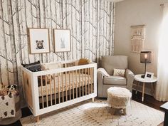 a baby's room is decorated in neutrals and white with trees on the wall