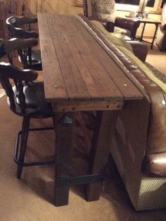 a long wooden table sitting in the middle of a room next to two leather chairs